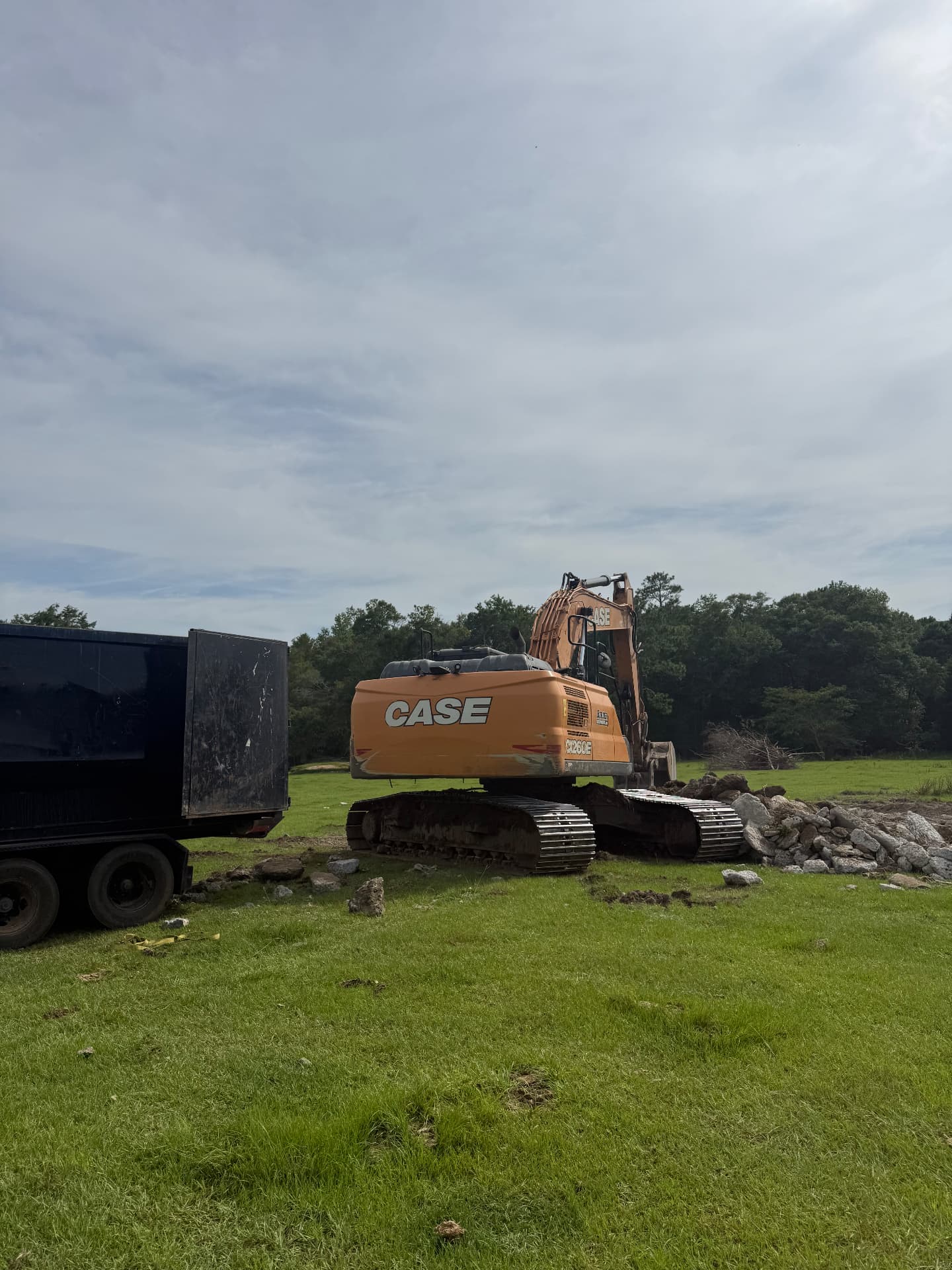 Excavator and dump trailer on a land clearing job site